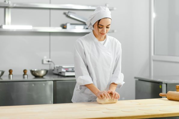 Woman cook kneads dough in the kitchen. The concept of semi-finished products