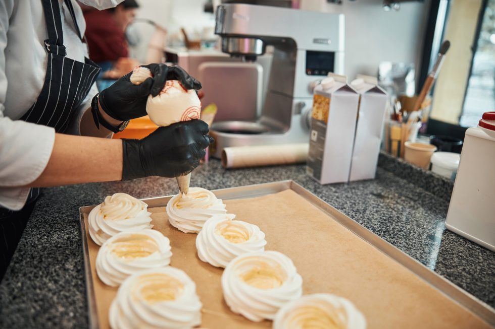 Certified pastry chef adding filling to meringues from confectioner syringe