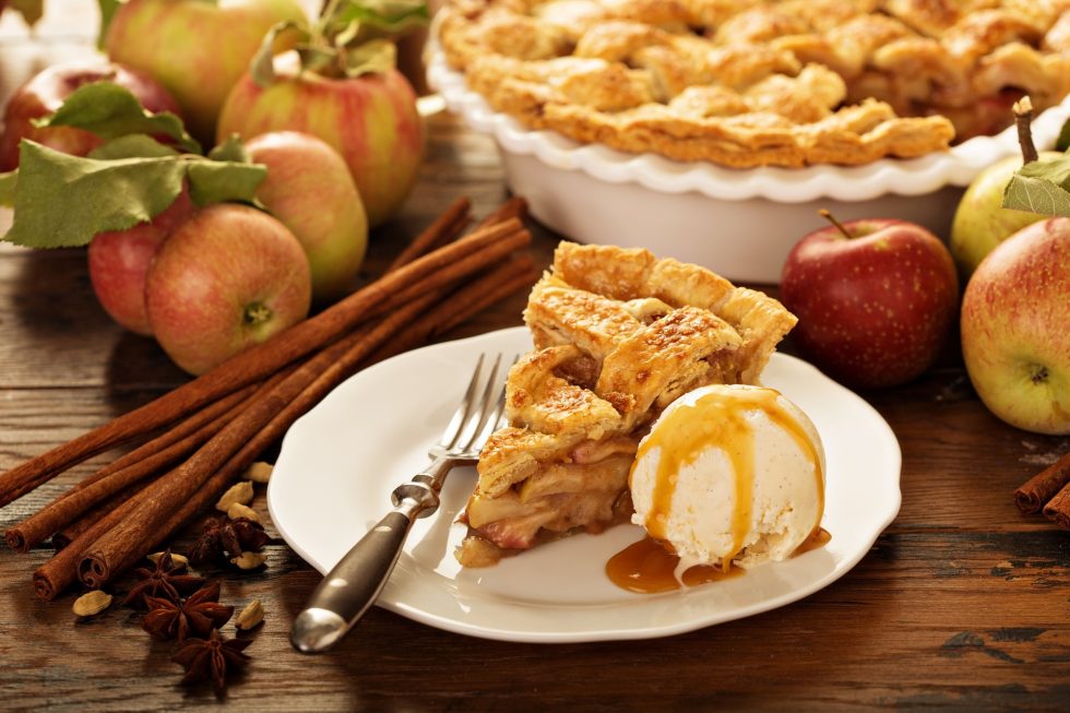 Piece of an apple pie with ice cream on a plate
